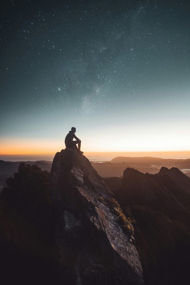 Man sitting on a cliff watching sunset