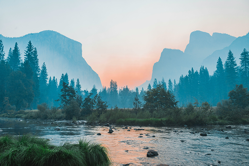 A view of mountains at sunset with a blue and green colors.
